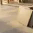 Keramische terrastegels in betongrijs en zandtint, gestapeld in een verspringend patroon met smalle voegen in warm natuurlijk daglicht.
